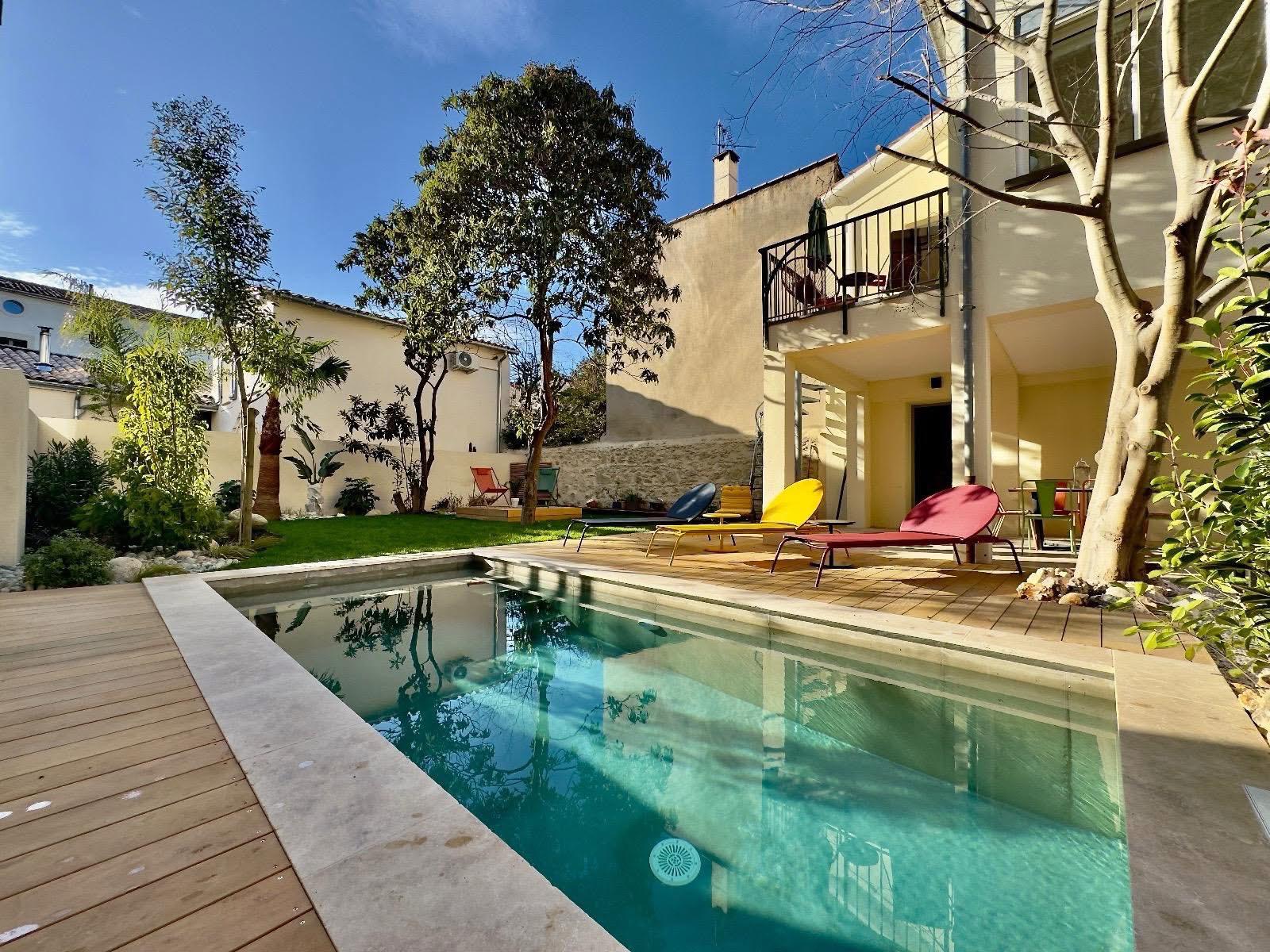 Piscine béton sur-mesure, plage en bois et margelles pierre dans un jardin méditerranéen