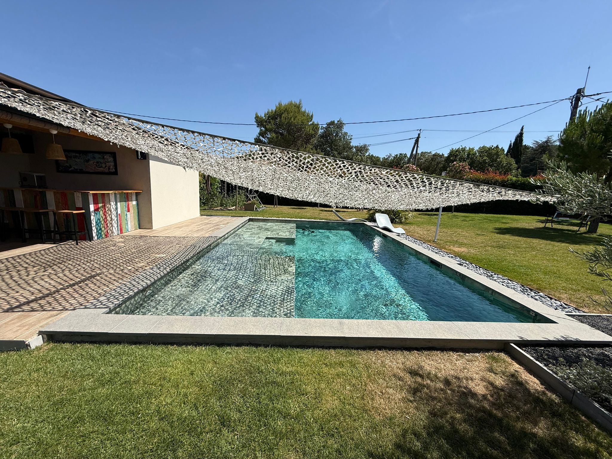 Piscine béton Reflets d’ici, terrasse bois et jardin méditerranéen